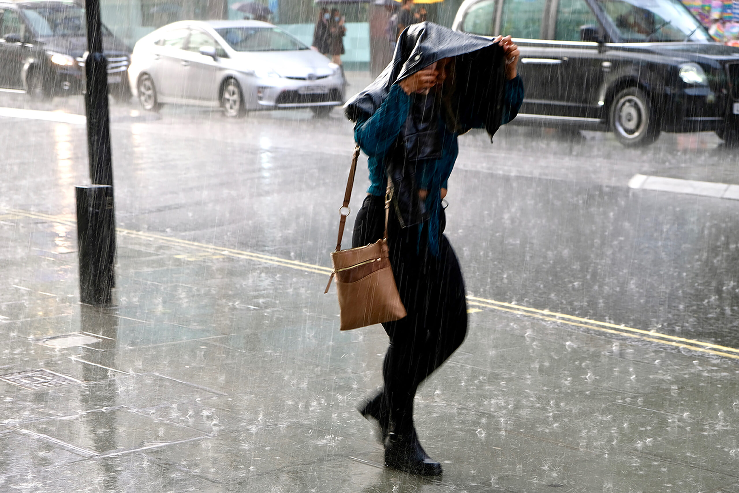 Woman walking in heavy rain on Oxford Street, London.